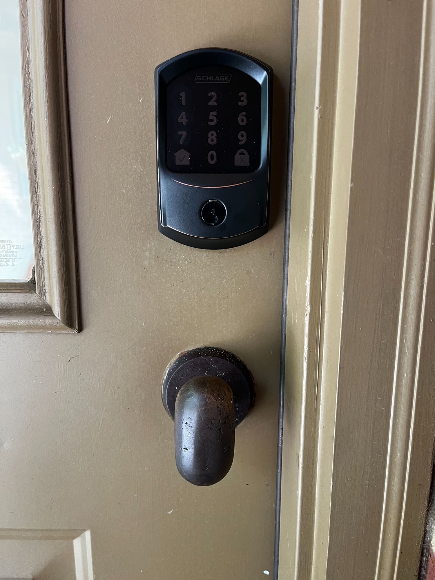 Schlage digital keypad lock mounted on tan door frame above interior deadbolt handle